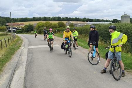 Riders spread out along an empty road with countryside around