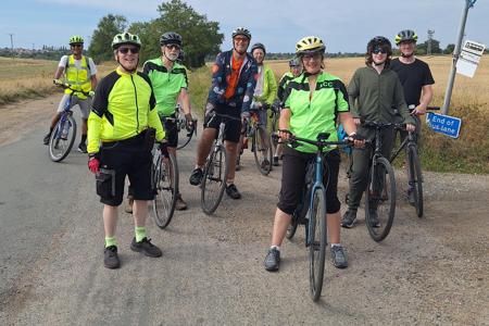 Riders stopped in a country lane.  On the right there are signs 'Bus Stop' and 'End of bus lane', although it's doubtfull if there has ever been a bus service here!