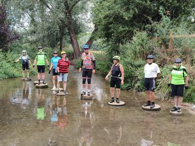 Riders standing on stepping stones across the River Ver